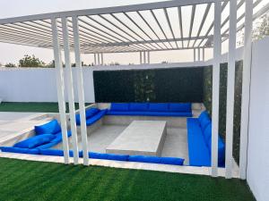 a pergola with a blue couch on a patio at Falaj Hub Retreat in Umm Al Quwain