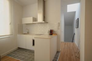 a white kitchen with white cabinets and a wooden floor at Villa Conde in Hospitalet de Llobregat