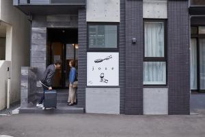 札幌的住宿－PINN-N4E2Ⅰ，站在房子外带手提箱的人
