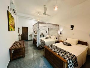 una habitación de hotel con 2 camas y un banco en Nature House, en Udawalawe