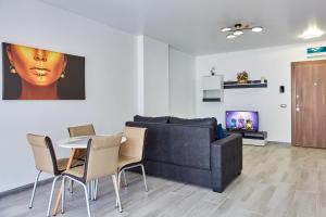 ein Wohnzimmer mit einem Sofa, einem Tisch und Stühlen in der Unterkunft Apartamente Nord 10 in Năvodari