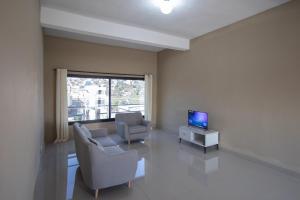 sala de estar con 2 sillas y TV en Milestone City - Appartements à louer, en Antananarivo