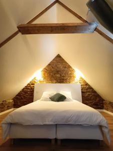 a bedroom with a white bed in an attic at Gîte Ti Laouen in Plélo