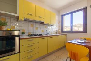 a yellow kitchen with yellow cabinets and a table at Appartamento Galileo Deluxe - MyHo Casa in Tortoreto Lido
