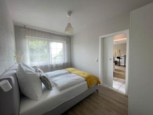 a white bedroom with a bed and a window at Das Haus am Weinberg in Ensch