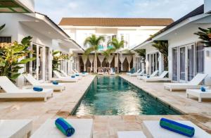 a pool in the middle of a resort with lounge chairs at Cocotoa Boutique Hotel & Villa in Gili Trawangan