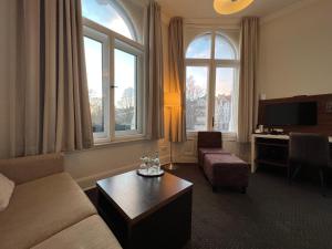 - un salon avec un canapé, une table et des fenêtres dans l'établissement Hotel Excellent, à Lübeck