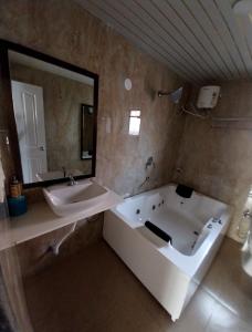 a bathroom with a tub and a sink and a mirror at Mango Valley Resort Ganpatipule in Ratnagiri