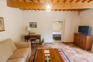 ein Wohnzimmer mit einem Sofa und einem Tisch in der Unterkunft Appartamento con piscina e giardino - Olivo in Ghizzano
