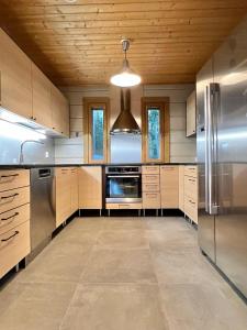 uma grande cozinha com electrodomésticos em aço inoxidável e tectos em madeira em Saimaan Villa Mustikka em Äitsaari