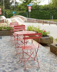 una fila di tavoli e sedie rossi con parco per skateboard di B&B Funtanin a Cuggiono