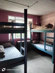 a room with three bunk beds and a window at PATHI BUNKERS in Darjeeling