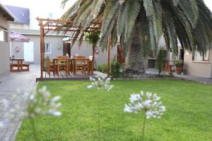 a garden with a table and chairs and a palm tree at The Mole Guesthouse in Swakopmund
