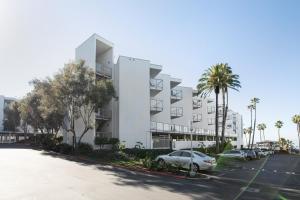 biały apartamentowiec z samochodami zaparkowanymi na parkingu w obiekcie Redondo Beach 1BR w Pool Gym WD nr Beach LAX-614 w mieście Redondo Beach