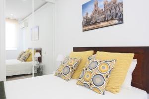 um quarto branco com uma cama com almofadas amarelas em Sol Apartment Deluxe-Nuñ-Arce em Madrid