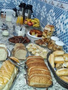 Hotel Porto Real في Pôrto Real: طاولة بها العديد من الأنواع المختلفة من الخبز والمعجنات