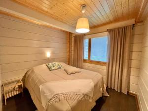 een slaapkamer met een bed in een kamer met een raam bij Saimaan Villa Mustikka in Äitsaari
