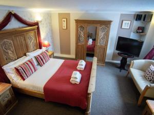 a bedroom with a bed and a couch and a television at The Heath Inn in Leighton Buzzard