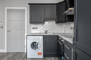 a kitchen with black cabinets and a washing machine at Modern spacious Belfast city stay free parking in Belfast