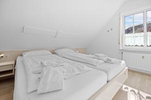 a white bed in a room with a window at Ferienwohnung Wohlfarth in Hooksiel