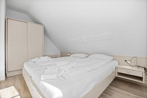 a white bed in a white room with a mirror at Ferienwohnung Wohlfarth in Hooksiel