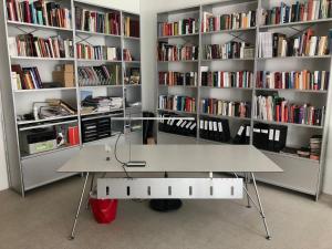 a book shelf filled with books in a room with a desk at Design Loft in ehemaliger Spinnerei in Mels