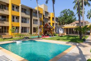 una piscina frente a un edificio con parque infantil en Cosy 2BHK With WIFI From Anjuna Vagator, en Anjuna