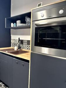 uma cozinha com um forno de aço inoxidável e um lavatório em Appartement lumineux et spacieux em Charleville-Mézières