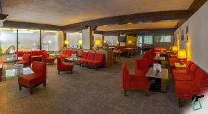 a lobby with red chairs and tables and a restaurant at HOTIDAY Residence San Martino in San Martino di Castrozza