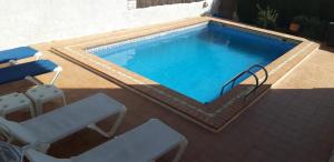 a swimming pool with two chairs and a table at Casa Magnolia in Dúrcal