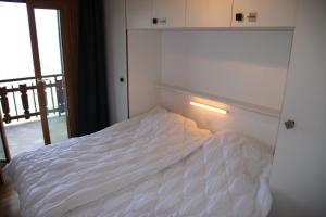 een wit bed in een kamer met een raam bij Greppons O 031 - MOUNTAIN apartment 10 pers in Veysonnaz