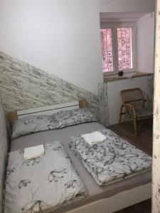 drie bedden in een kamer met een stoel en een raam bij Apartment Ida in Piran