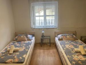 2 camas individuales en una habitación con ventana en Retro Panzió, en Pécs