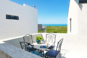 a table and chairs on a balcony with the ocean at Agulhas Seabreeze, tip of Africa in Agulhas