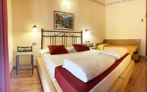 um quarto com 2 camas com lençóis brancos e almofadas vermelhas em Hotel Rabay em Brenzone sul Garda