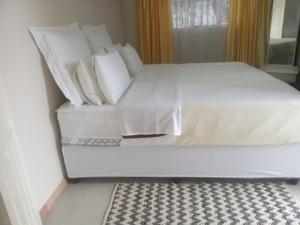a large white bed with white pillows and a rug at Cottage on 14th in East London