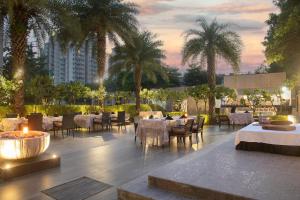 阿格拉的住宿－阿格拉萬怡酒店，一间设有桌椅的餐厅,种植了棕榈树