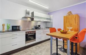 une cuisine avec des placards blancs et une table en bois dans l'établissement Pet Friendly Apartment In Zeulenroda-triebes With Wifi, à Zadelsdorf