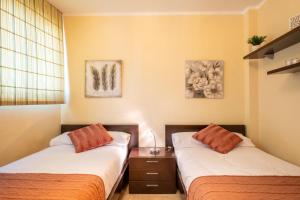 サンタクルス・デ・テネリフェにあるCentrico apartamento en Santa Cruz de Tenerifeのベッド2台、テーブル、写真2枚が備わる客室です。