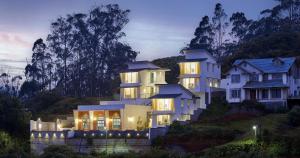 una gran casa blanca en una colina por la noche en Clouds Nest By Aanvis Inn en Ooty