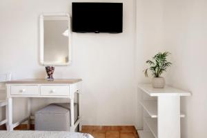 a bedroom with a white dresser and a tv on a wall at Eleni's Garden 3 in Alikanas