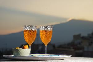 twee champagneglazen op een bord met een fruitschaal bij Opuntia Charming Rooms in Taormina