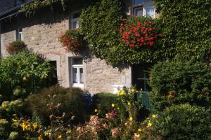 a stone house with flowers in front of it at Bei Ulla und Willi auf dem Land in Aachen