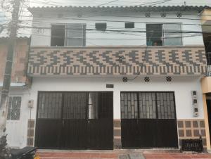 a white house with black doors and a balcony at Apartamento independiente para pareja con cocina in Villavicencio