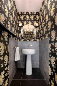 La salle de bains est pourvue d'un lavabo blanc et de fleurs sur les murs. dans l'établissement Agora' - Boutique Stays, à Turin