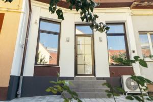 a house with three windows and a staircase at The Middle House in Satu Mare