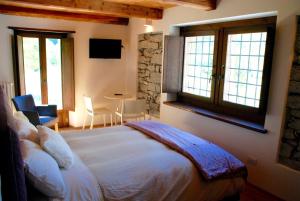 ein Schlafzimmer mit einem großen weißen Bett in einem Zimmer mit Fenstern in der Unterkunft Ca' del Borgo in Cadarese