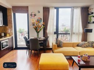 ein Wohnzimmer mit einem gelben Sofa und einem Tisch in der Unterkunft Home suites -Natural light -Projector -Spacious - 2BR incenter in Hanoi