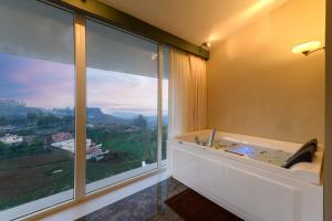 Camera con vasca e ampia finestra. di Clouds Nest By Aanvis Inn a Ooty