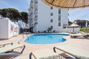 een zwembad met stoelen en een gebouw bij Hotel Best Terramarina in La Pineda